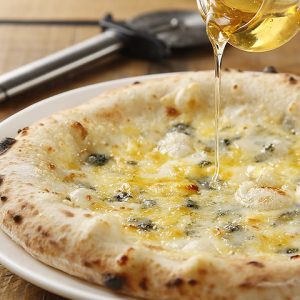 立川駅1分 本格パスタが美味しいイタリアン＆スパニッシュのお店『CANTINA 立川店』でいただける、ゴルゴンゾーラなどのチーズが乗ったクワトロフォルマッジョのピザの上に蜂蜜がかけられているところ